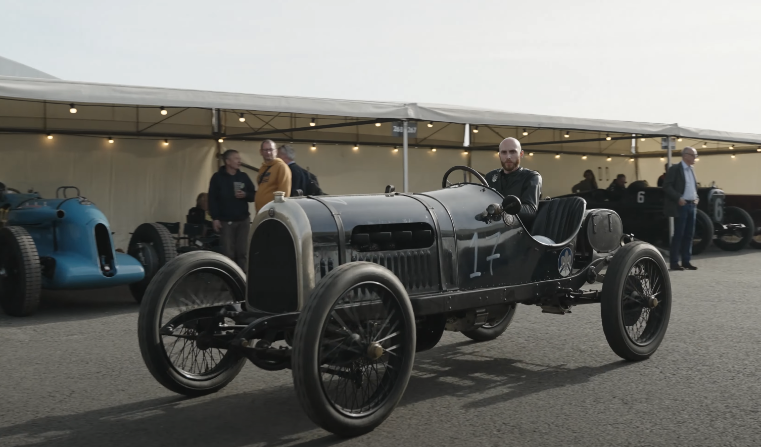 Blue 1913 Pre-War race car drives through the pits at Goodwood